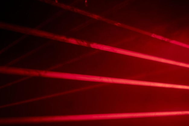 Luci laser al neon rosse luminose illuminano l'oscurità creando linee e forme triangolari in un effetto fantascientifico.