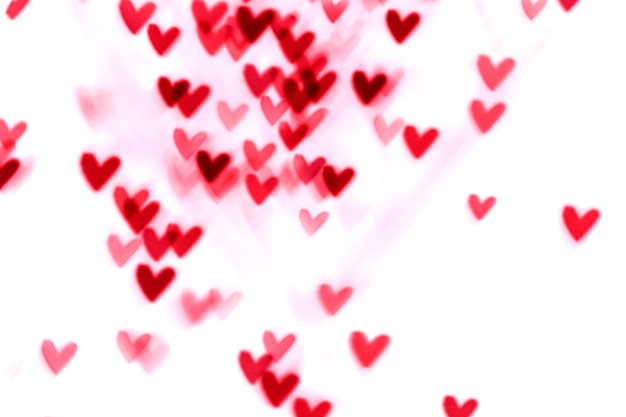 Luci rosse del bokeh del biglietto di S. Valentino del cuore contro una priorità bassa bianca