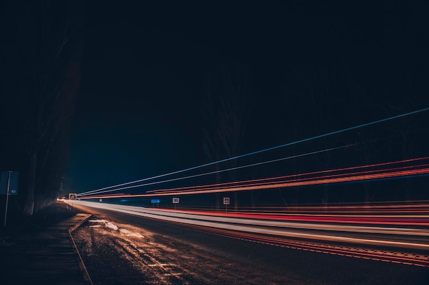 Luci rosse e bianche delle auto di passaggio. Autostrada notturna.