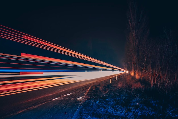 Luci rosse e bianche delle auto di passaggio. Autostrada notturna.