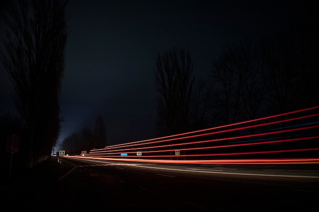 Luci rosse e bianche delle auto di passaggio. Autostrada notturna.