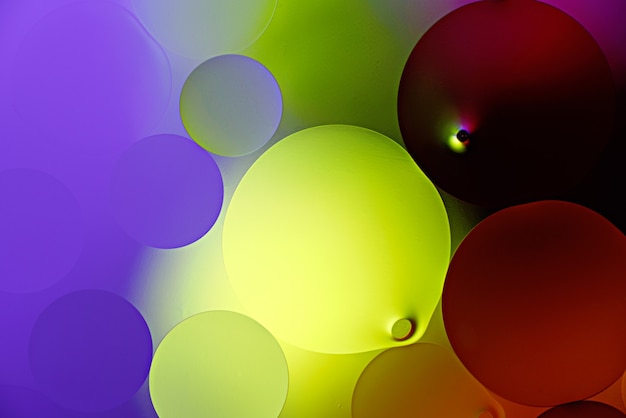Luminoso neon incandescente bolle sfere di goccioline di olio sulla superficie dell'acqua, sfondo astratto