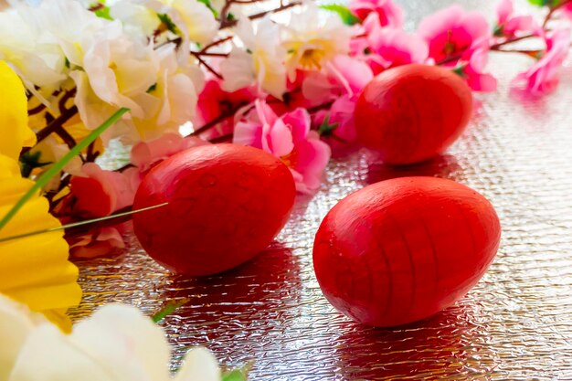 Luminoso sfondo di Pasqua argento decorato con nastri di fiori e uova rosse Una carta di soggiorno