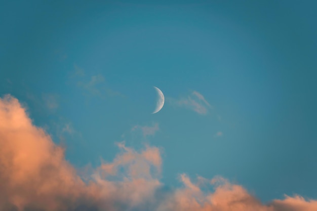 Luna crescente incandescente e nuvola serale sul cielo blu