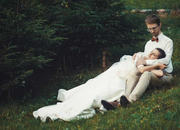 Luna di miele. La sposa e lo sposo seduti sull'erba. Estate.