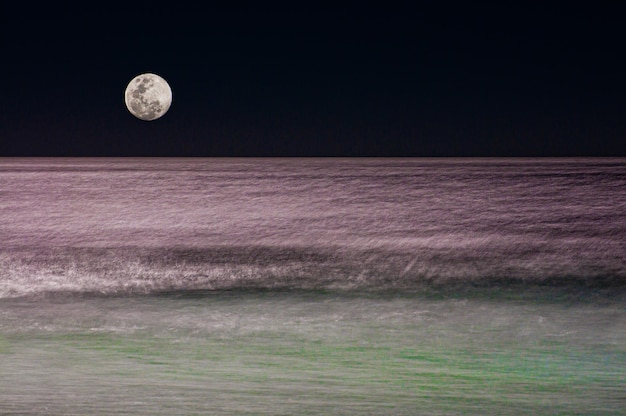 Luna piena che si riflette nel mare in un giorno di sbornia su una spiaggia brasiliana