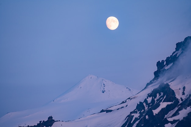 Luna piena d'oro che sorge su montagne lontane nell'ora blu