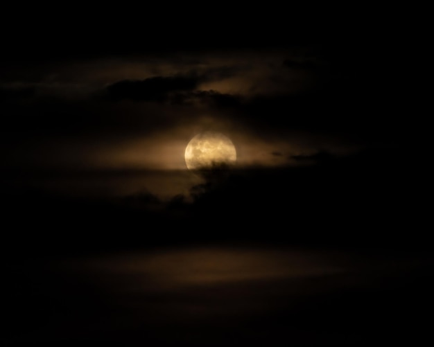 Luna piena dietro le nuvole sul cielo nero Cielo drammatico Cielo di orrore Serenità sullo sfondo della natura