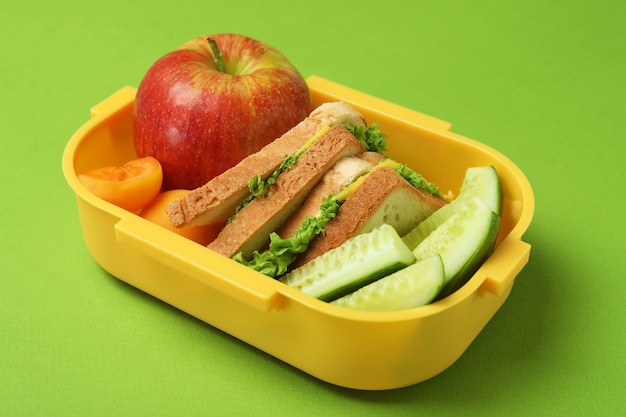 Lunch box con cibo gustoso su sfondo verde