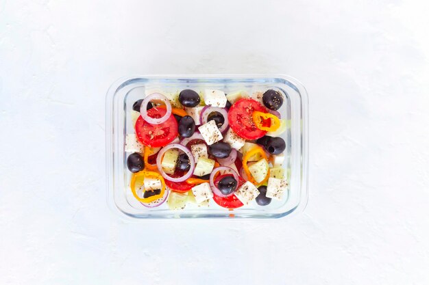 Lunch box con insalata greca su sfondo bianco