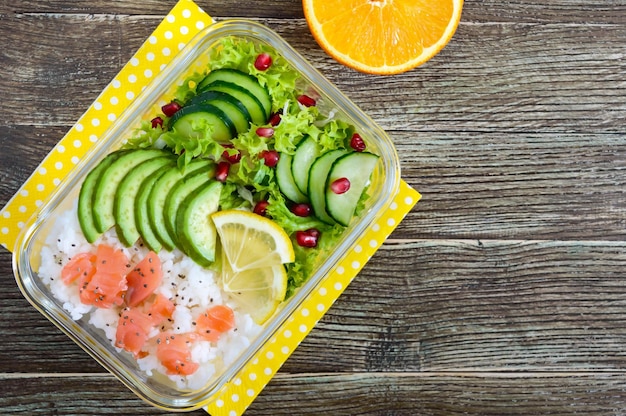 Lunch box riso salmone insalata con cetriolo avocado verdi limone arancia fresca acqua