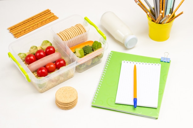 Lunchbox scuola sul tavolo con penna per taccuino e bottiglia di yogurt