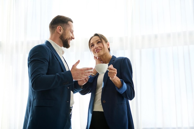 Lunghezza alla vita di bell'uomo e bella donna, partner commerciali, colleghi durante la pausa caffè. Capo e dipendente che flirtano al lavoro. Concetto di partnership, lavoro di squadra e leadership di successo sul lavoro