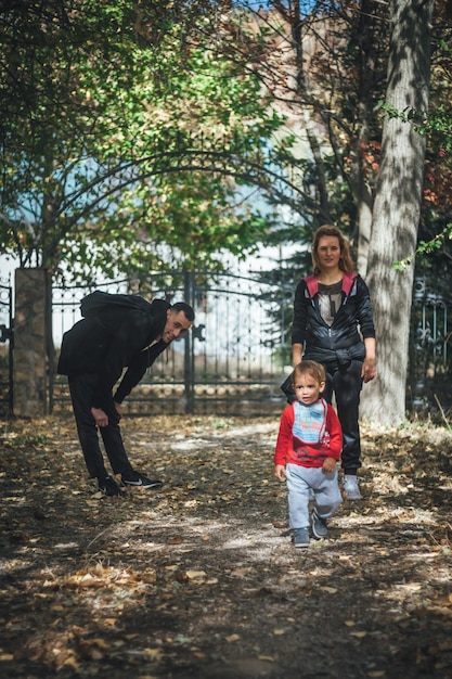 Lunghezza completa dei genitori che guardano il figlio che cammina nel parco durante l'autunno