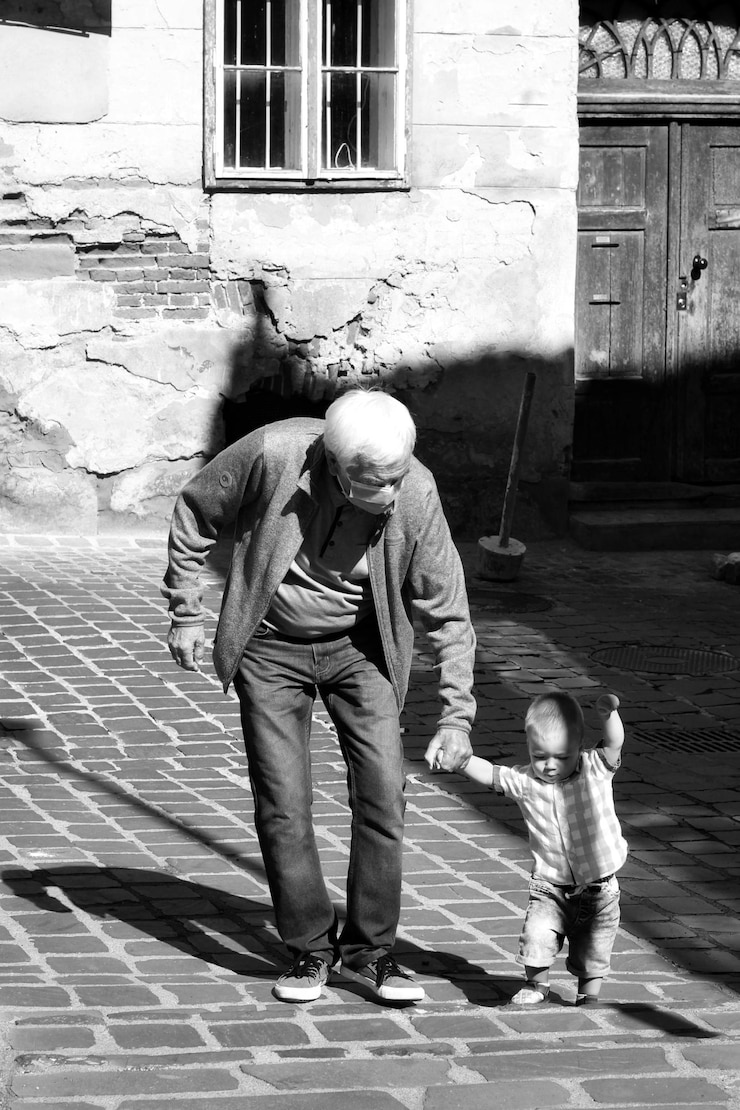 Foto lunghezza completa del nonno che indossa la maschera per il coronavirus e del nipote all'aperto