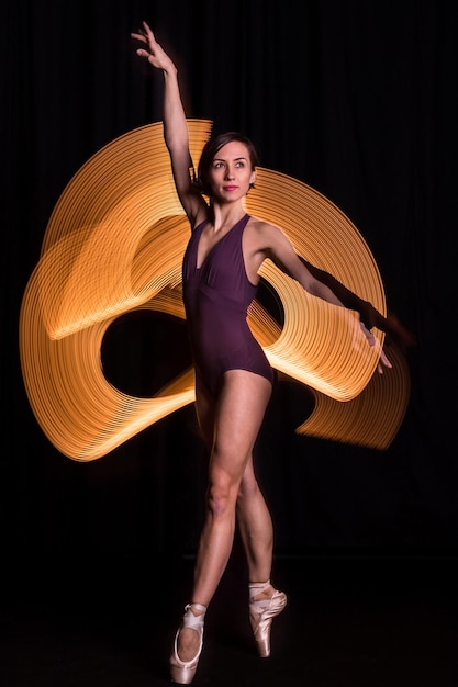 Lunghezza completa della ballerina contro la pittura luminosa