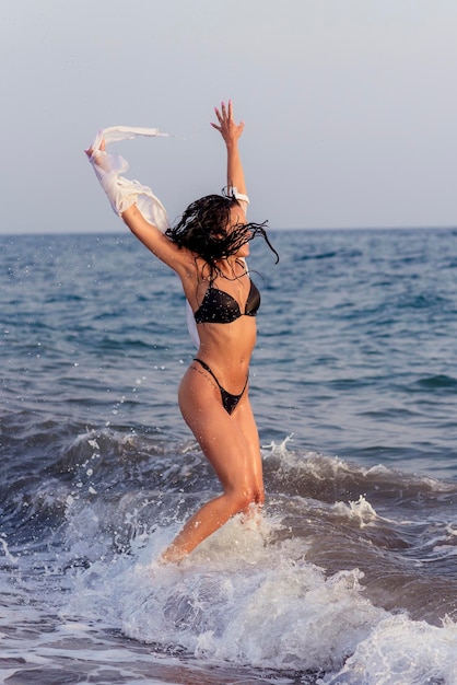 Lunghezza completa di donna con le braccia alzate che salta in mare