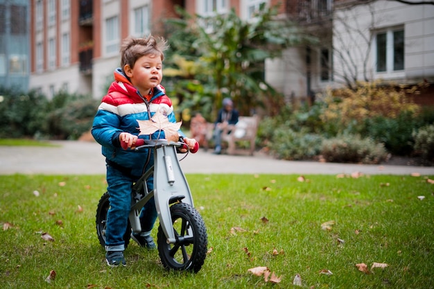 Lunghezza completa di un ragazzo con una bicicletta in piedi sul prato