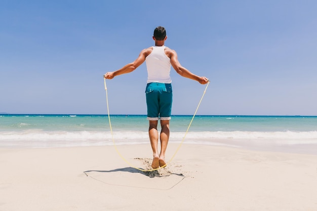 Lunghezza completa di un uomo che si esercita sulla spiaggia contro un cielo limpido