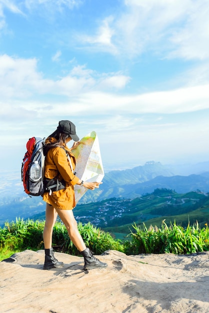 Lunghezza completa di una donna che tiene in mano una mappa mentre sta in piedi sulla montagna contro il cielo