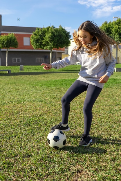 Lunghezza completa di una donna con la palla sul campo da calcio