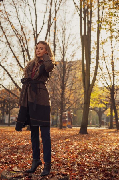 Lunghezza completa di una giovane donna in piedi nel parco durante l'autunno