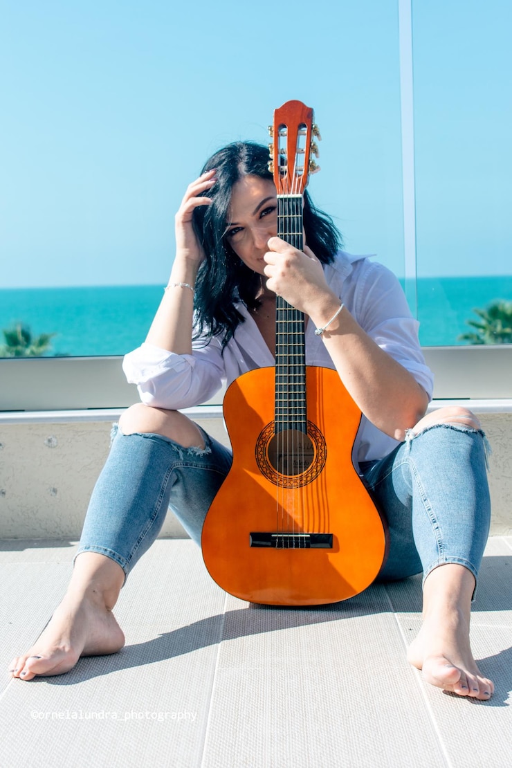 Foto lunghezza completa di una giovane donna seduta alla chitarra