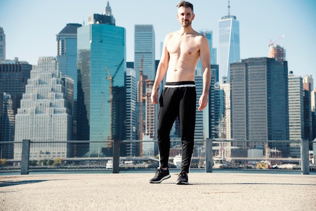 Lunghezza completa di uomo senza camicia in piedi sulla terrazza dell'edificio in città