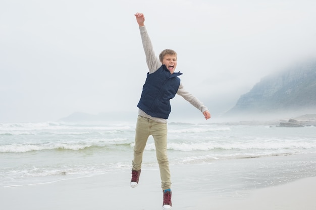 Lunghezza totale di un ragazzo casual saltando in spiaggia