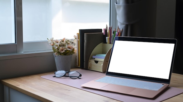 Luogo di lavoro contemporaneo con computer laptop occhiali tazza di caffè e forniture Schermo vuoto per il montaggio di display grafici