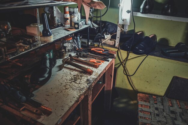 Luogo di lavoro del calzolaio con gli strumenti necessari su di esso in un'officina buia.