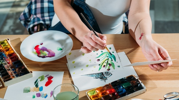 Luogo di lavoro dell'artista con bozze e forniture di tavolozza in giro. Pittore che fa le pennellate di schizzo ottenendo ispirazione.