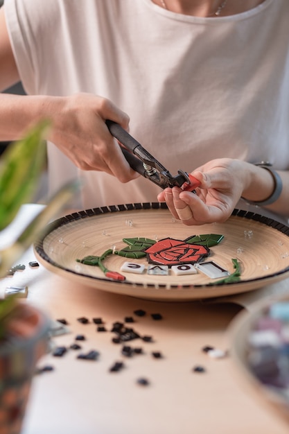 Luogo di lavoro di un maestro del mosaico: mani femminili che dispongono un elemento di mosaico sul tavolo