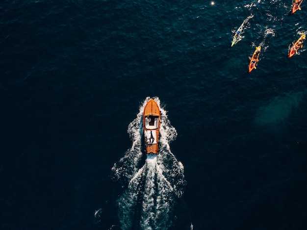 Lussuosa barca a motore in legno si precipita tra le onde del mare Adriatico. I turisti navigano in kayak a remi.