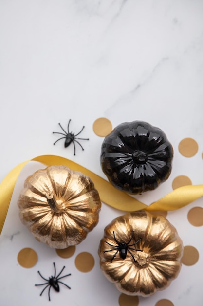 Lussuosa composizione piatta di zucca autunnale in oro e nero su uno sfondo di marmo