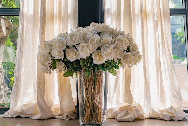 Lussureggiante bouquet di rose bianche in un vaso alla luce del sole