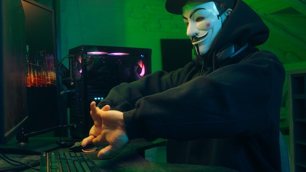 Lviv ukraine june masked man anonymous stretching fingers programmer hacking typing computer malware