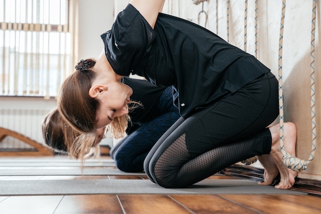 Lyengar gruppo femminile di yogi che praticano esercizi di ginnastica in studio di yoga appeso a una parete con