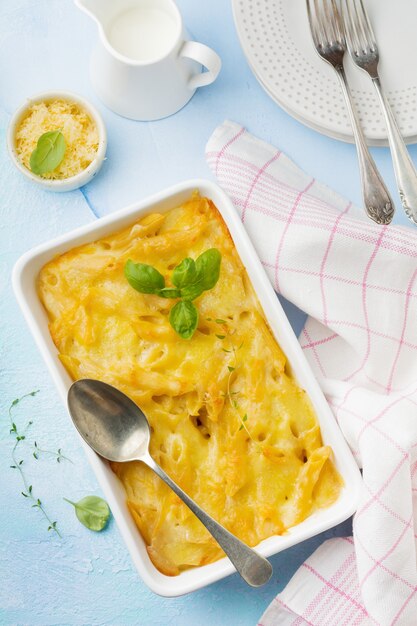 Mac e formaggio. Casseruola di pasta, formaggio e besciamella in forma di ceramica su cemento leggero o pietra.