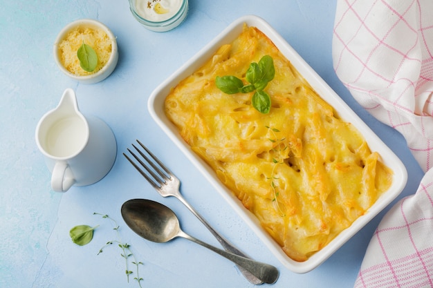 Mac e formaggio. Casseruola di pasta, formaggio e besciamella in forma di ceramica su cemento leggero o pietra.