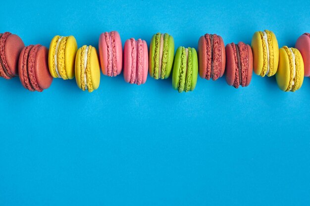 Macaron colorato o macaroon dolce confezione a base di meringa su sfondo blu Spazio per la copia del primo piano