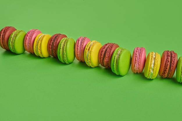 Macaron colorato o macaroon dolce confezione a base di meringa su sfondo verde Spazio per la copia del primo piano