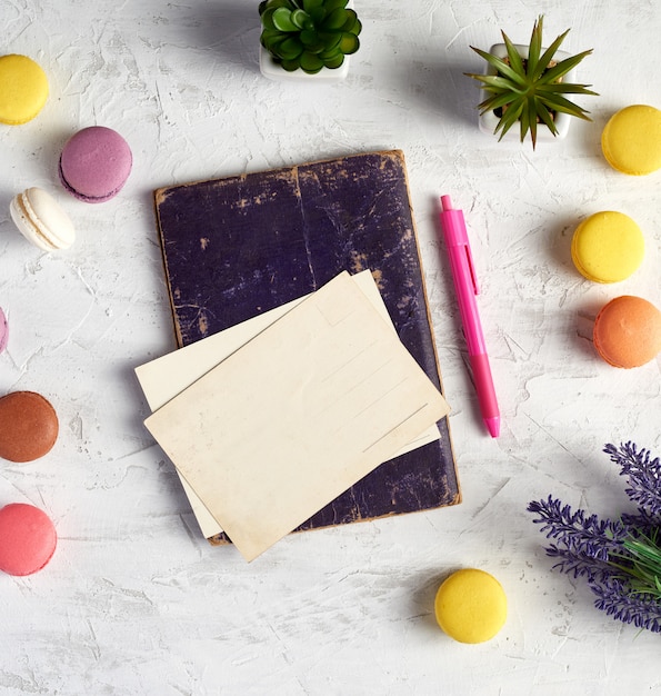 Macaron rotondi al forno, cartoline vuote, quaderno, penna rosa