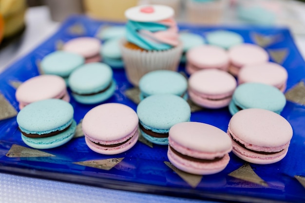 Macaroni e cupcake colorati disposti su un vassoio festivo blu