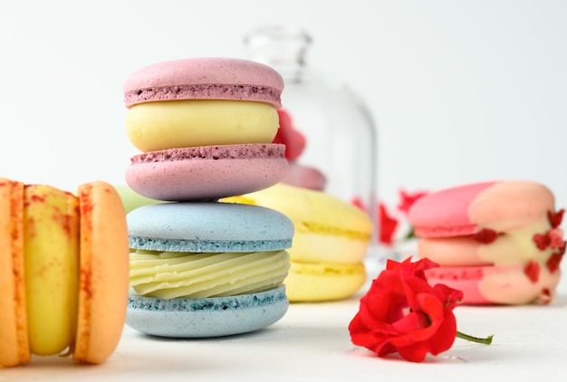 Macarons al forno e boccioli di rosa su un tavolo bianco, dessert gourmet di farina di mandorle, primo piano