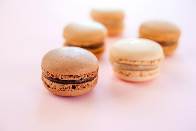Macarons francesi o amaretti con moka alla vaniglia e sapore di cioccolato su sfondo rosa