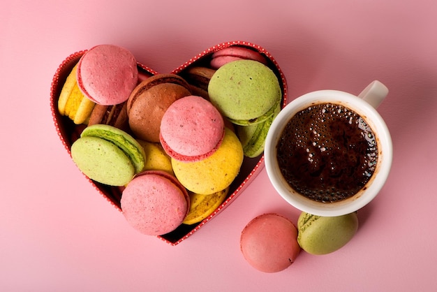 Macarons in confezione regalo con una tazza di caffè su sfondo rosa