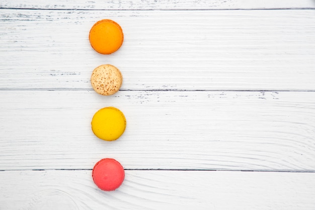 Macarons variopinti su fondo di legno bianco