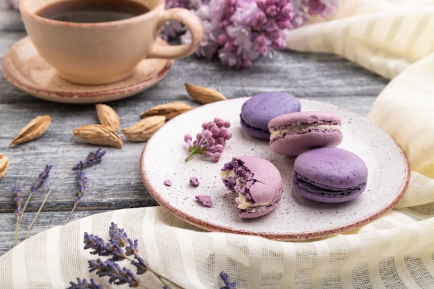 Macarons viola o torte di amaretti con una tazza di caffè su una superficie di legno grigia e tessuto di lino bianco