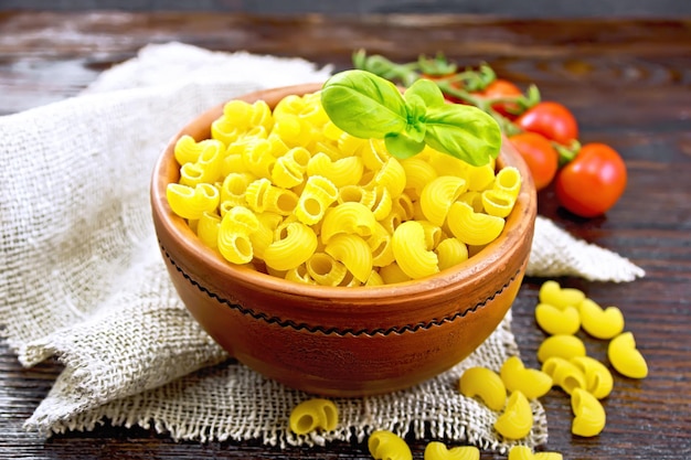 Maccheroni al gomito in una ciotola con pomodori e basilico a bordo